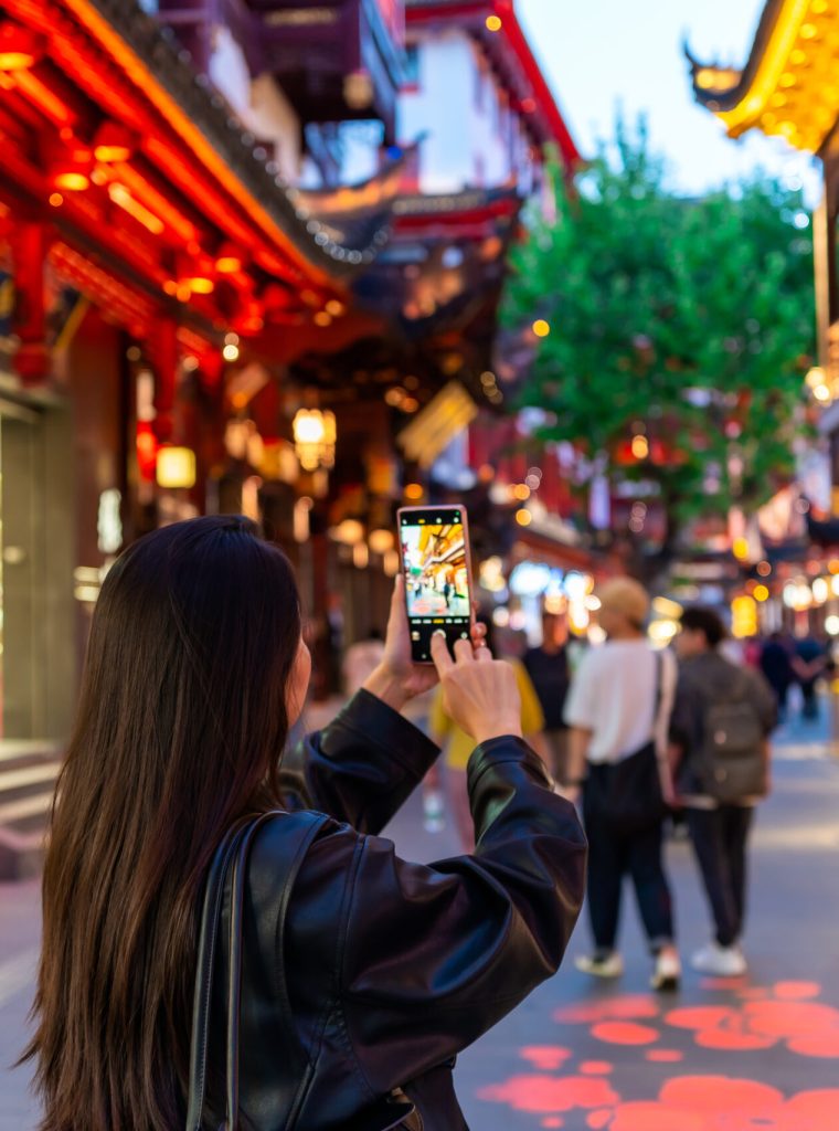 Young female tourist taking a photo of the Yuyuan old street in Shanghai, China